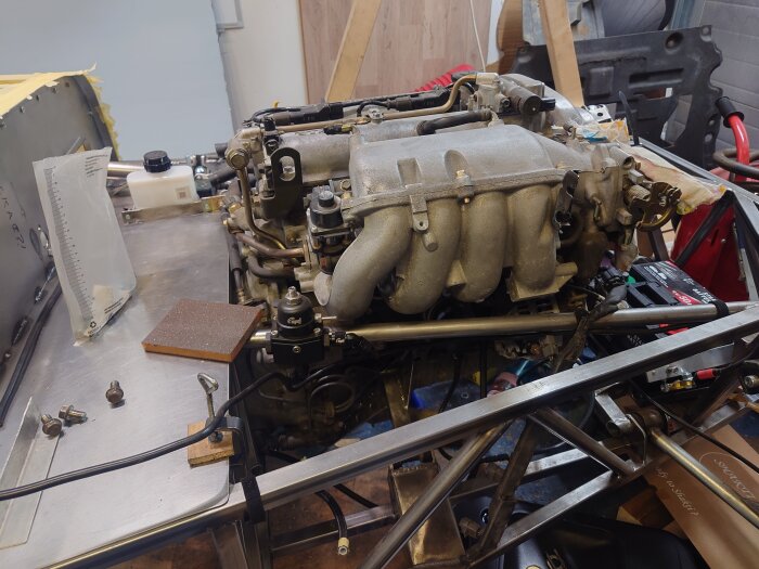 Motor från en Mazda Miata NB 1.8 liters radfyra monterad på arbetsbänk i verkstad med verktyg och komponenter runtom.