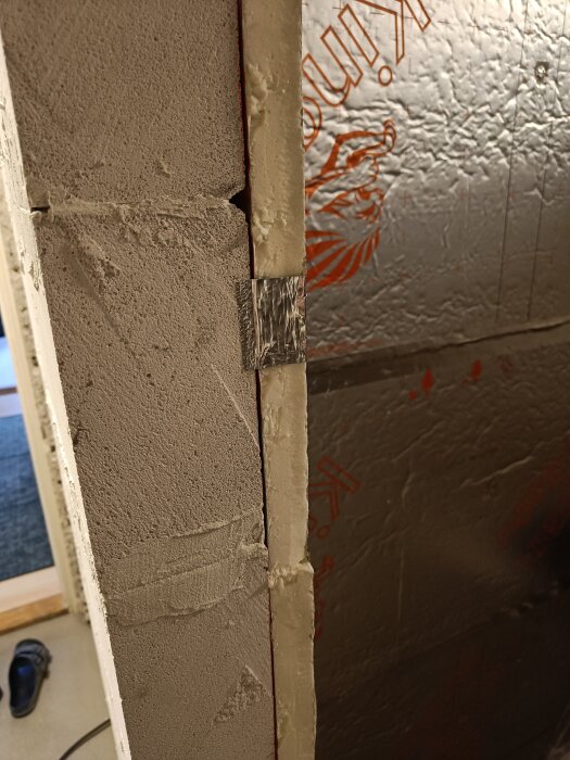 Lättbetongvägg vid dörrpost med sauna satu-isolering och aluminiumtejp över skarven för tätning.