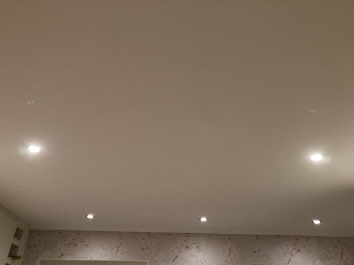 Fem takspottar med varierande ljusstyrka i ett rum, några verkar lysa svagare.