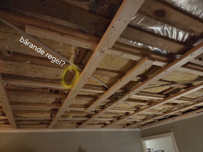 Byggtak med reglar och isolering synliga, markerad "bärande regel?", antyder pågående renoveringsarbete.