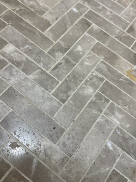 Kalkstensgolv med fläckar och märken efter rengöring, bild tagen nära för struktur och färgdetaljer.