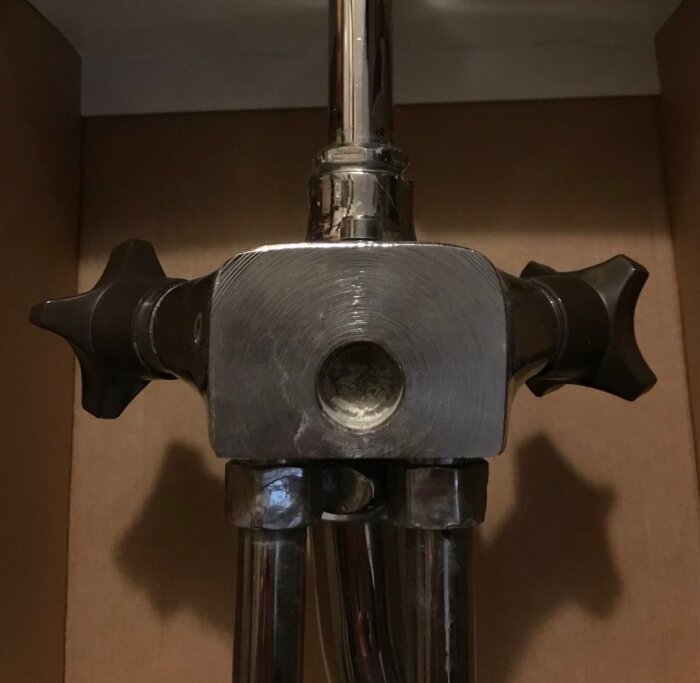 Gammal metallblandare med två svarta vred, fotograferad framifrån, utan synligt väggfäste.