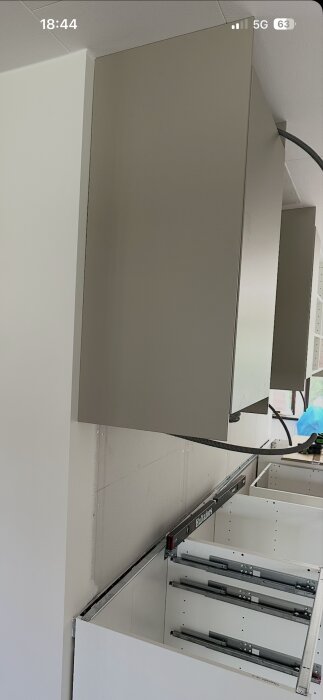 Väggskåp i kök med glipa på 5-6 mm mellan skåpets överkant och taket, här visas snedställd täcksida och nedre del med lådskenor.