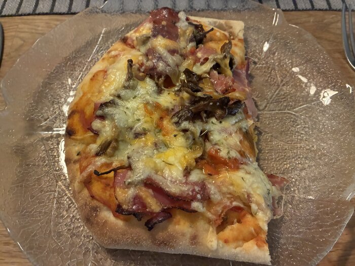 Pizza med porfini och tryffelsås, kantareller, pepparsalami, kallrökt skinka och ost, serverad på en glasfat.