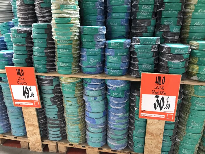 Staplar med isolerade kablar i olika färger, märkta med priser i en spansk butik.