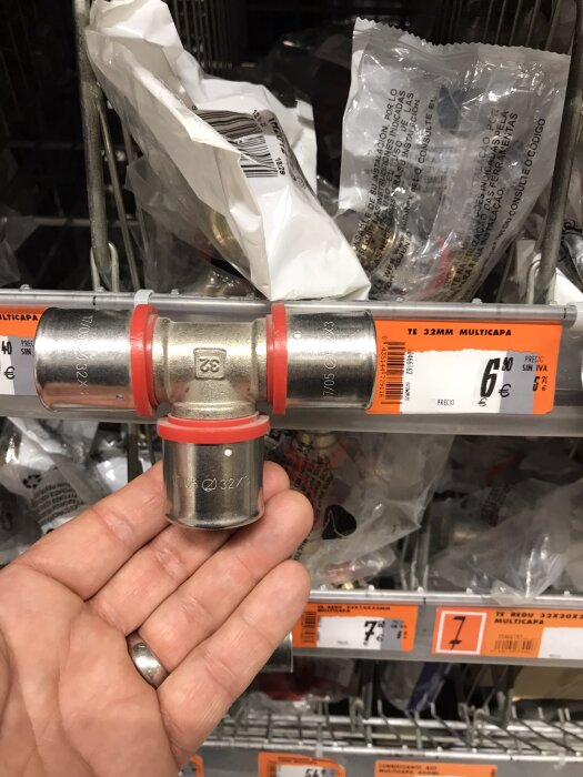 Rörkoppling i metall med röda tätningar, prissatt till 6 euro i en spansk butik.