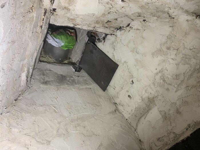 Sidovy av öppen eldstad med delvis blockerat rökrör och sotiga ytor.