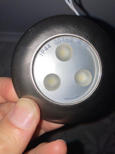 LED-spotlight i ett svart hölje med texten "IP44 0.01m" på ytan, visas i en hand.