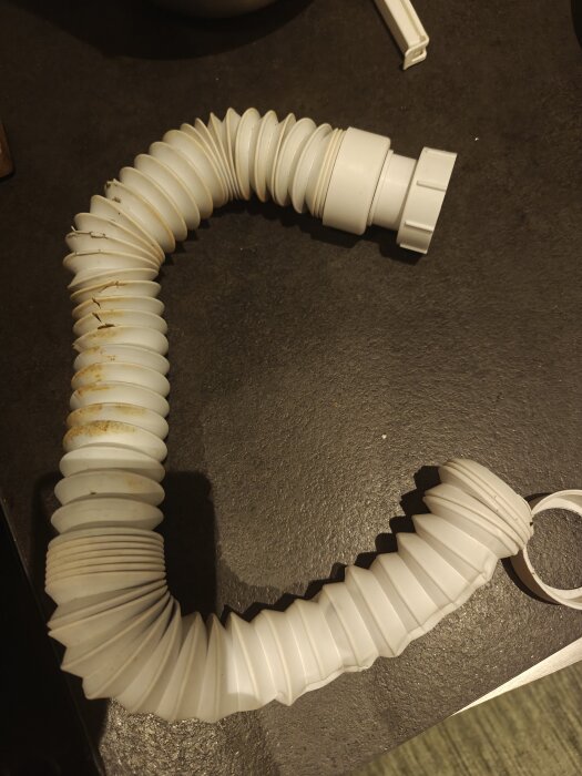 Trasig flexislang från under diskbänk, synlig skada och slitage.