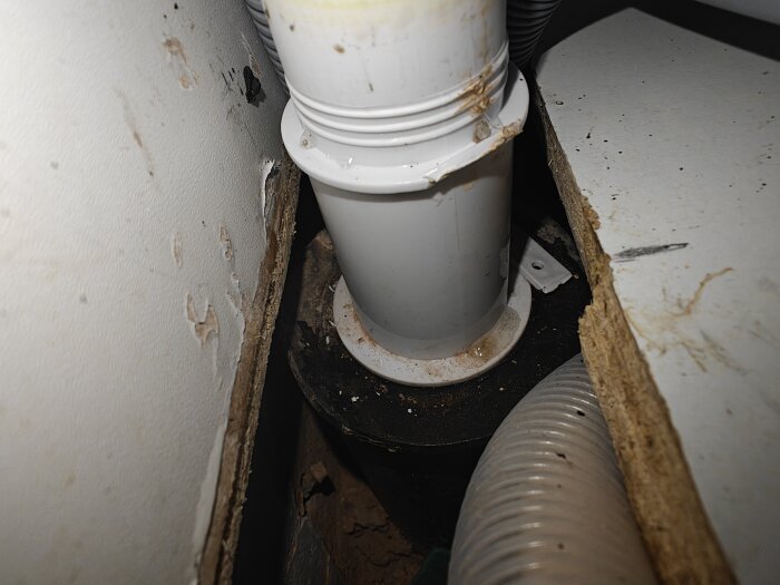 Flexislang och plastdelar under ett tvättställ med synliga skador och missfärgning.