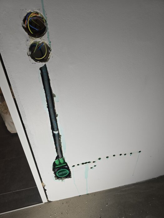 Vägg förberedd för elinstallation med två eldosor och dragna kablar. Hål borrade i väggen för kabeldragning och anslutning av eluttag.