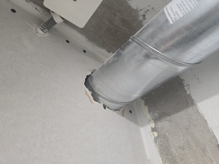 Rörinstallation genom gipsskiva med spikhål i närheten, samt synlig kopplingsdosa.