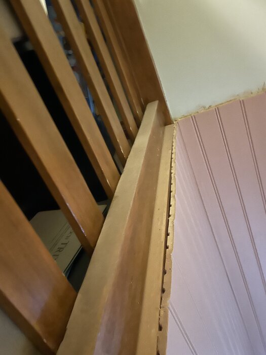 Trästruktur vid trapphål med träspjälor och panelvägg, inför installering av nytt golv och räcke på övervåningen under renovering.