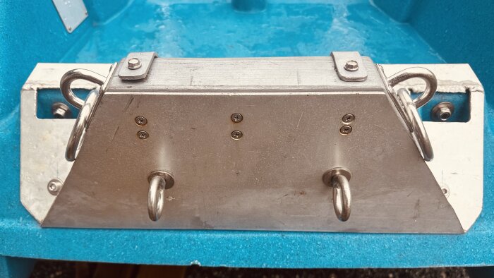 Motorfäste i aluminium med fyra fästöglor monterat på en blå båt.