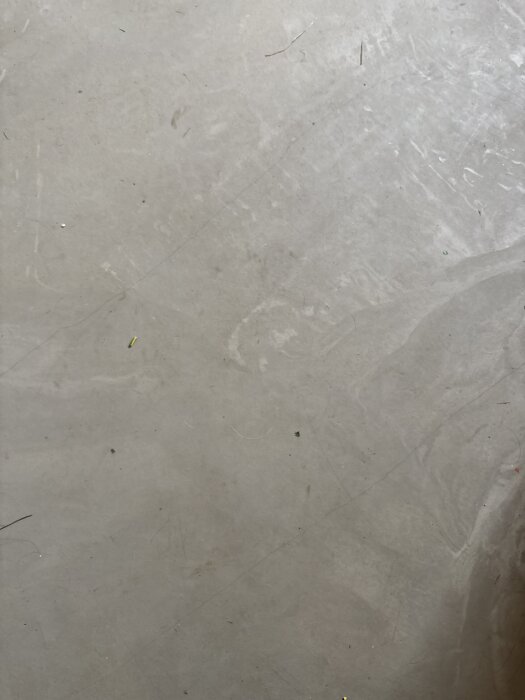 Sprickor i ett grått flytspackel på en golvyta efter att värmen slagits på över elgolvslingor.