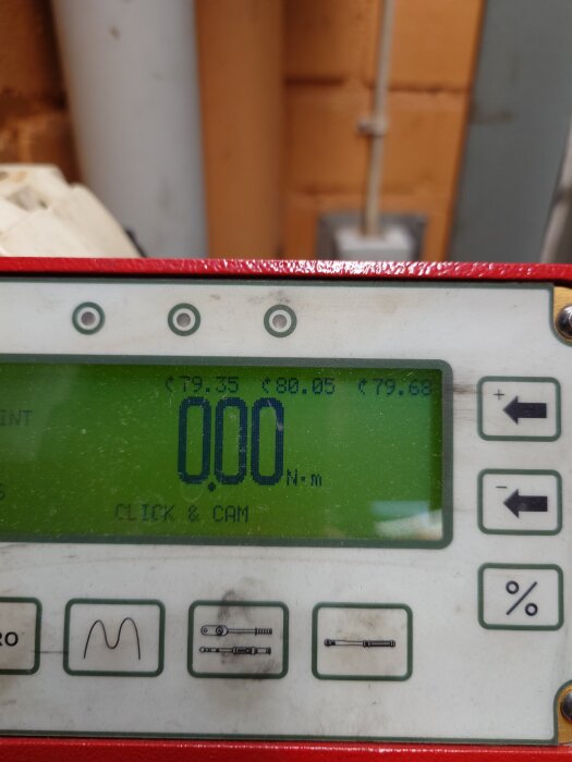 Digitalt momentverktyg som visar 0,00 Nm på en skärm med knappar och inställningar för momentstyrka, placerad i en verkstadsmiljö.