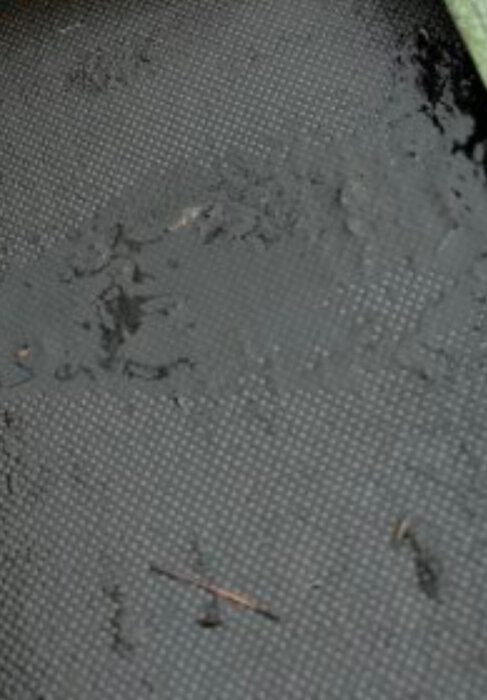 Blött område på svart material med vattenläckage.