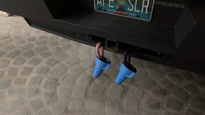 Bakre delen av ett fordon med två hitch balls täckta av blåa skydd och en registreringsskylt ovanför.