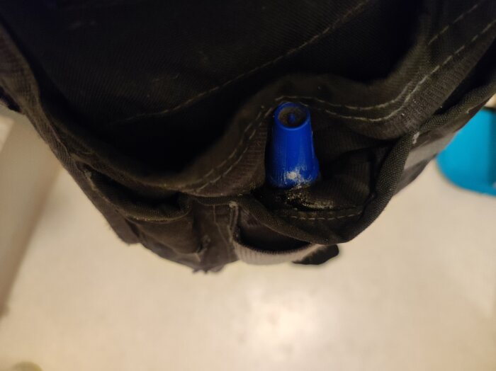 Blå limflaska i tygficka, som illustrerar att Loctite 406 cyanidlim för plast även fungerar på tygmaterial.