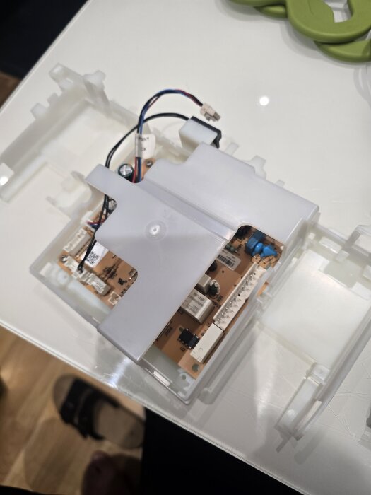 Elektronisk kretsmodul i plastkapsling med kablar anslutna på ett bord.