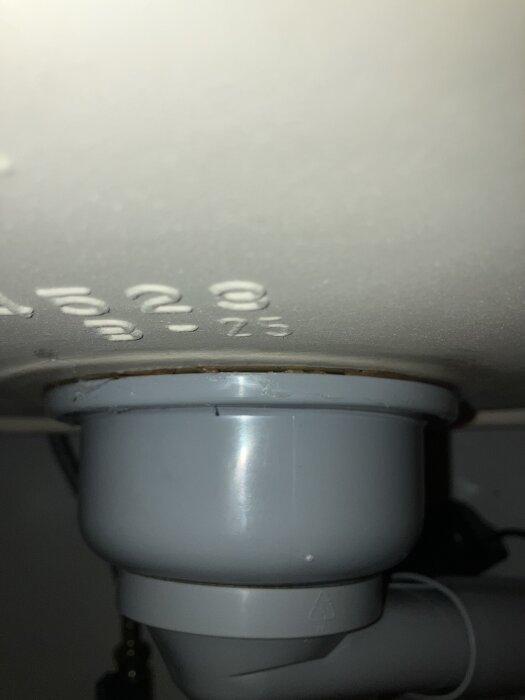 Under diskbänk med synlig silikon och potentiellt läckage runt röranslutning.