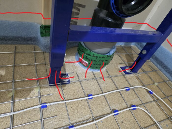 Montering av ram för en vägghängd toalett med synlig golvvärmeinstallation och tätskikt på golvet. Röda linjer markerar möjliga borrhål.
