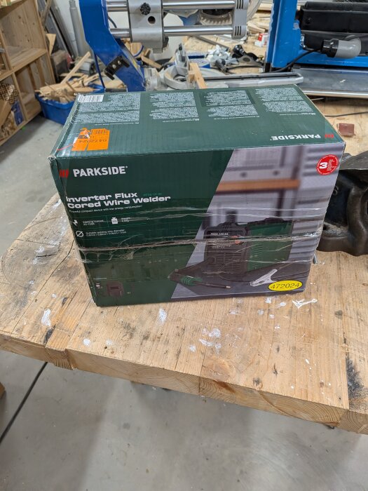 Kartong med en Parkside inverter flux cored wire welder på ett arbetsbord i en verkstadsmiljö.