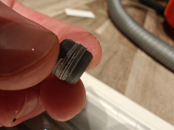 Närbild på en hand som håller en liten svart plastkomponent, som verkar vara en del av Ikeas lådsystem.