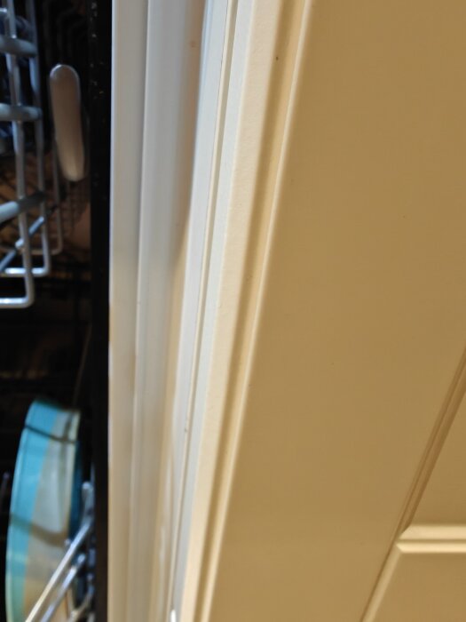 Öppen diskmaskin med synlig turkos tallrik i korgen, skjutdörr till höger.