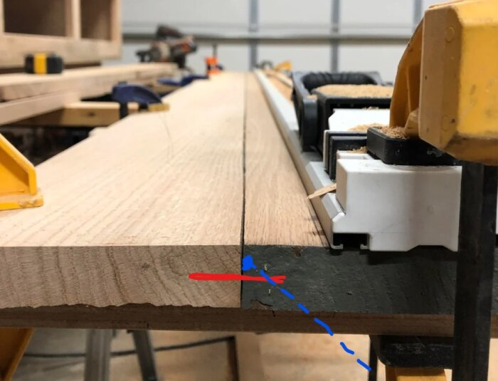 Gammalt furugolv håller på att monteras upp, med skråad spik synlig mellan plankor. Gula klämmor och arbetsplats i bakgrunden.