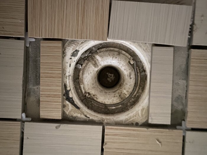 Klinkerplattor löst placerade runt ett brunnslock för illustration av installation på plastunderlag. Rund brunn i mitten med olika klinkerstorlekar.