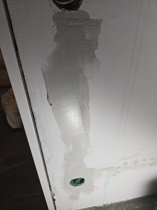Vägg med nyligen applicerat spackel runt ett nytt eluttag, oslipad yta; förberedelser för målning.