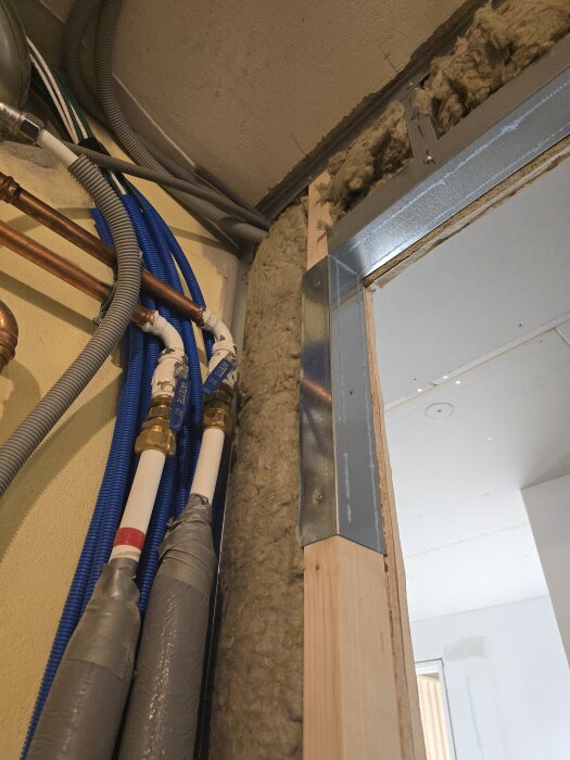 Isolerade rör och flexrör synliga i väggram med OSB och gipsskivor under installation i ett hobbyrum/gym.