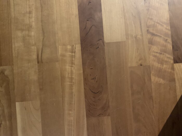 Tarkett trägolv i körsbärsträ visas i närbild. Golvet består av ljusa och mörka träplankor med naturliga mönster och texturer.