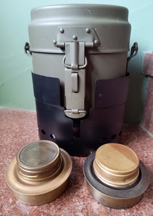 En klassiskt konstruerad enmanskök med brännare och två spritbrännardelar, placerade på ett bord.