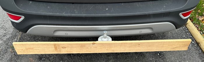 Träbräda monterad på en bils dragkrok bak, visar ett koncept för att skapa en avtagbar ramp för hundar.