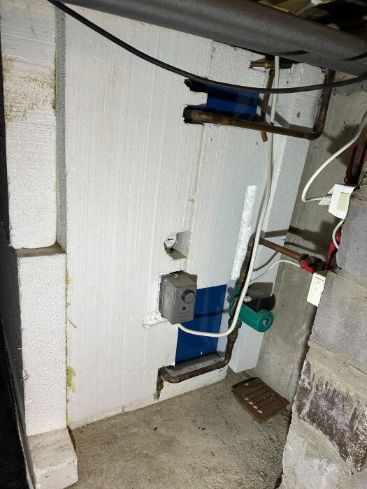 Ackumulatortank med kopparrör, kopplingar och pump i ett fritidshus.