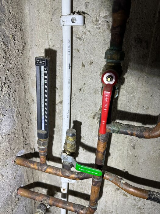 Rörsystem med termometer, shuntventil och metallrör i ett fritidshus. Termometern visar temperatur i celsius.