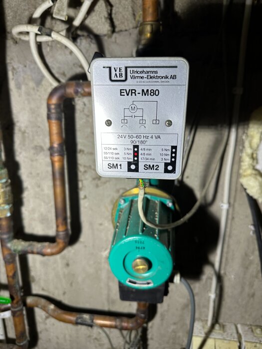 Shuntventil och rörledningar i ett fritidshus med märkningen EVR-M80 på ventilens styrbox.