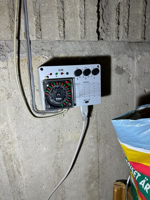 Tidstyrningstermostat med rattar och skala monterad på vägg.