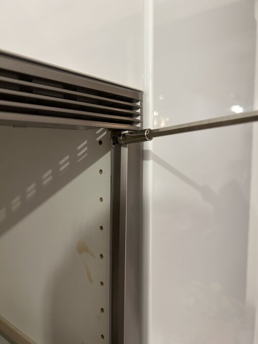 En mejsel används för att bända loss sidopanelen på en köksapparat.