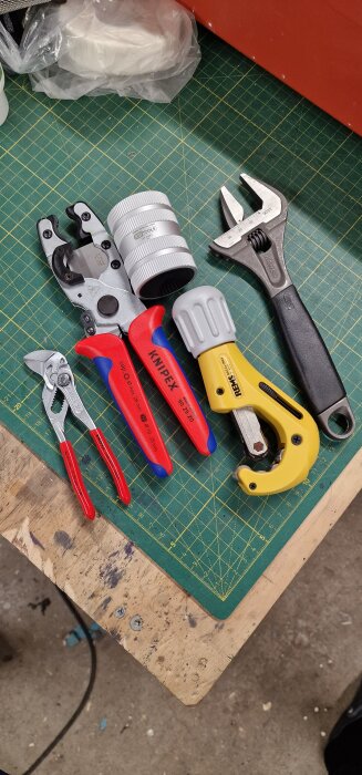 En samling VVS-verktyg pÄ ett arbetsbord, inklusive en justerbar skiftnyckel, rörtÄng och andra olika handverktyg.