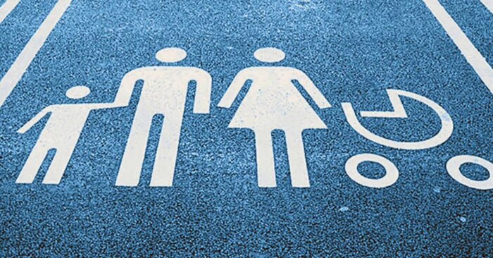 Symbol för familjeparkering med figurer av vuxna, ett barn och en barnvagn målade på marken.