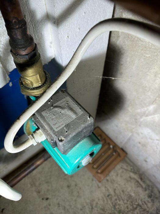 En pump i krypgrunden, kopplad till en vedeldad värmepanna, med vita och metalliska rör anslutna.