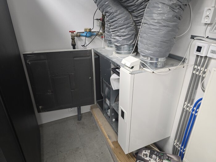 CTC-värmepump och ventilationsrör i maskinrum med klinkergolv och vattenmätare, redo för byte. Elsystem och FTX-aggregat synliga.