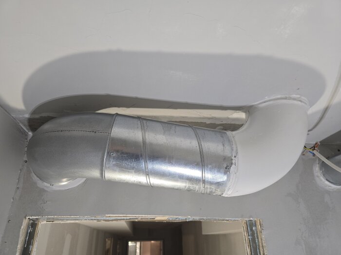 Ventilationsrör i källare, nytt gips och förberedelser inför målning. Rören är delvis grundmålade i en vit nyans.