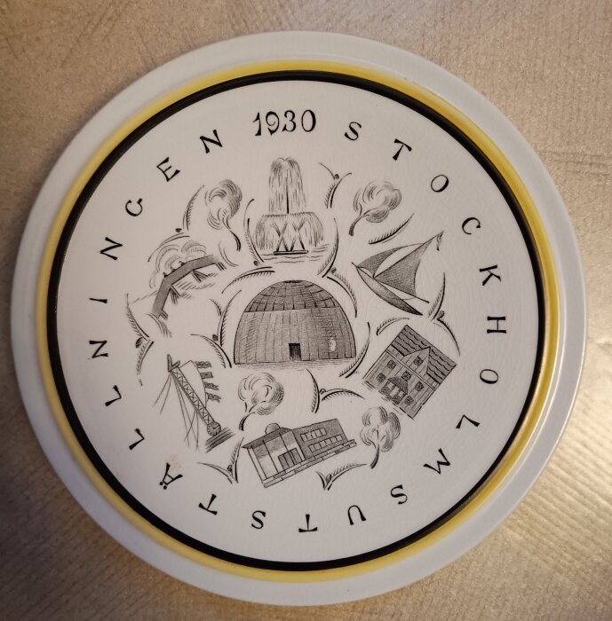 Tallrik med motiv från Stockholmsutställningen 1930, visar olika byggnader och symboler från utställningen, med texten "Stockholmsutställningen 1930".