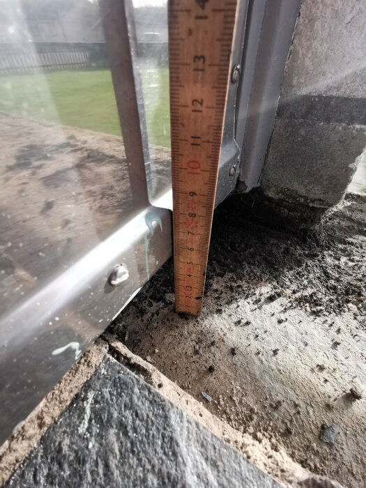 Måttstock visar höjdskillnaden mellan tröskeln och skifferplattorna på en entretrappa, där limningen har släppt och plattorna ligger lösa.