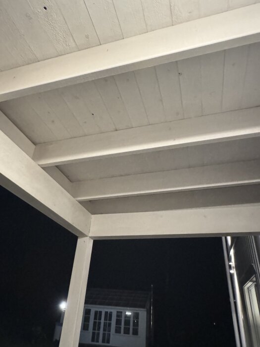 Tak och bjälklag i farstu, kvällstid, med utsikt över gården bakom.