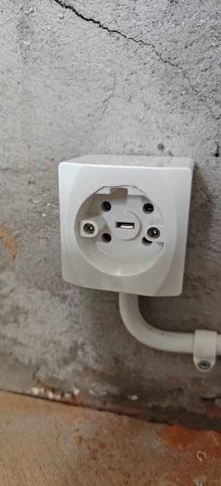 Vägguttag av märket Malmbergs monterat på betongvägg.